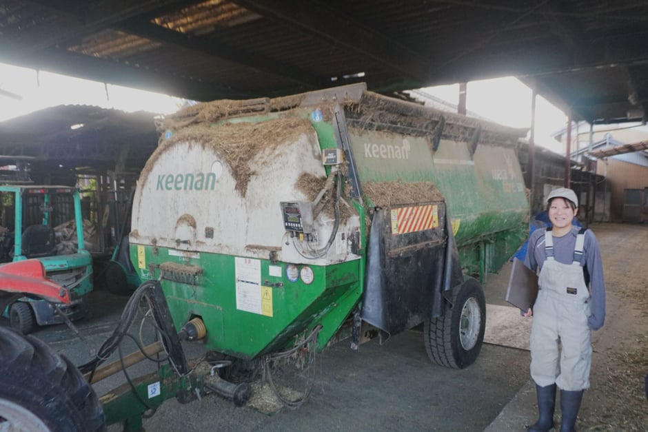 牧場を案内してくれた樹里さん。エサをつくる機械の前で